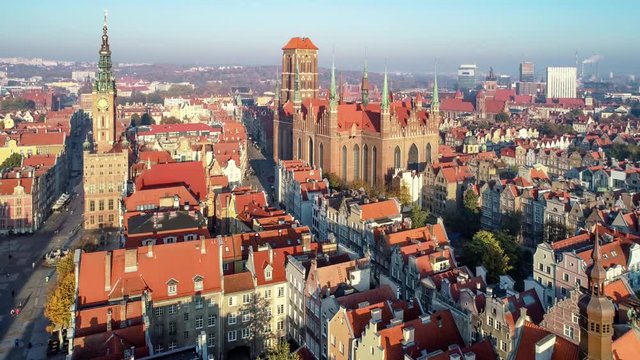 Gdansk, Poland. Old city with Gothic St. Mary church, city hall with clock tower, Dluga Street and old historic houses. Aerial approaching video in sunrise light.