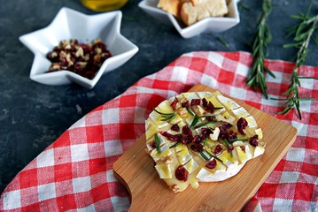 Baked camembert or brie with rosemary, garlic and olive oil. Served with dried cranberries, walnuts and white bread croutons.