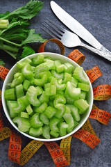 Chopped celery stalks in a bowl. Measuring tape. Concept of weight loss with celery.
