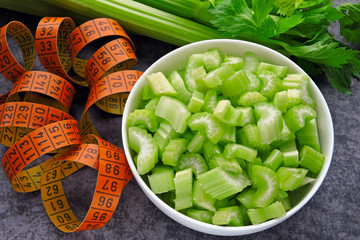 Chopped celery stalks in a bowl. Measuring tape. Concept of weight loss with celery.