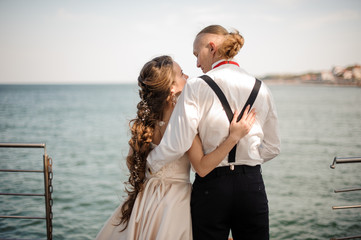 Back view of happy young married couple standing in the background of the sea