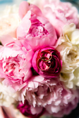 Fototapeta premium A pair of wedding gold rings on a bouquet of colorful flowers, close up shot