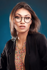 Fototapeta premium Portrait of a beautiful girl in round glasses on a blue background in the studio