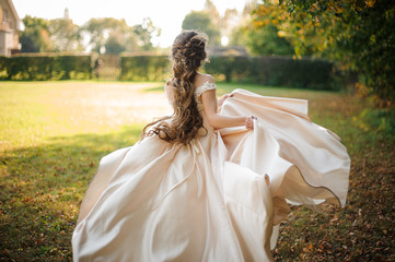 Back view of beautiful bride spinning in a wedding dress dancing on the green field