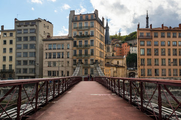 Pedestrian bridge Saint-Georges crossing the Saone river with the couple and old french Lyon city on the background.