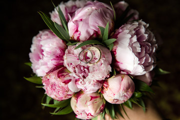 A pair of wedding gold rings on a bouquet of pink flowers, close up shot