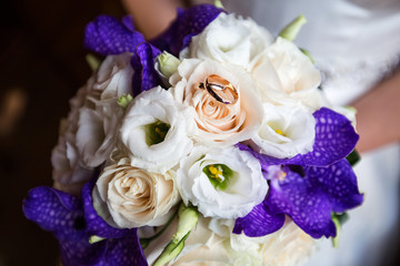 A pair of wedding gold rings on a bouquet of colorful flowers, close up shot