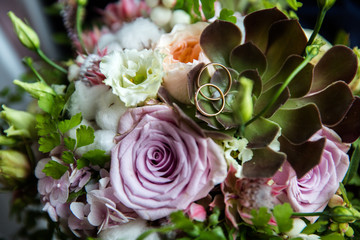 A pair of wedding gold rings on a bouquet of colorful flowers, close up shot