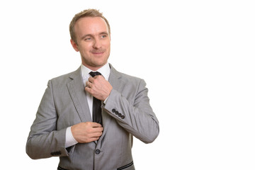 Handsome Caucasian businessman fixing his tie isolated against white background