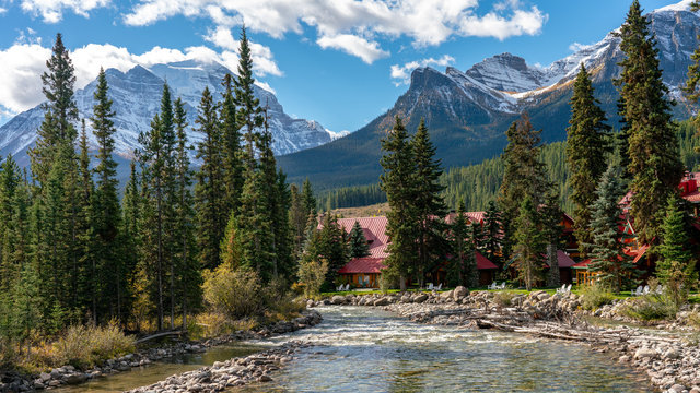RUNNING CLEAR WATER STREAM IN PINE FOREST WITH HIGH ROCKY MOUNTAIN BACKGROUND IN BANF NATIONAL PARK  , ALBERTA , CANADA