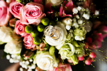A pair of wedding rings on a bouquet of colorful flowers, close up shot