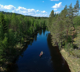 People on a canoe paddling a river in a forest.