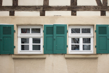 Old ancient wooden window with blinds or shutters. Scenic original and colorful view of antique windows in old city Sindelfingen, Germany. Isolated on wall. No people. Front view. Old fashioned style. - 243026710