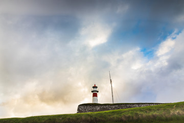 Lighthouse in Torshavn, the capital of Faroe Islands during sunset in summer with clouds in the sky. 