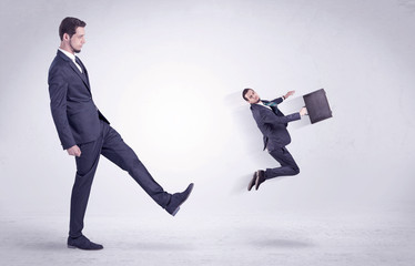 Big man in suit kicking out little himself out with simple white wallpaper
