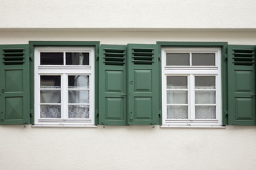 Old ancient wooden window with blinds or shutters. Scenic original and colorful view of antique windows in old city Sindelfingen, Germany. Isolated on wall. No people. Front view. Old fashioned style. - 243027939
