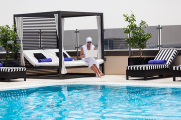 woman using laptop near to the swimming pool