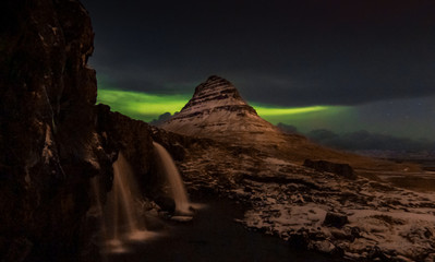 Kirkjufell mountain in Iceland at night in winter with northern light behind.
