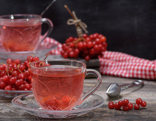 hot viburnum tea in a transparent cup with a handle and saucer