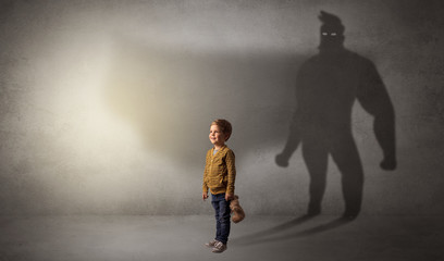 Cute kid in a room with plush on his hand and hero shadow on his background
