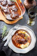 Traditionelle geschmorte Kalbsbäckchen in brauner Rotwein Sauce mit Kartoffel Püree als Draufsicht auf einem Zinnteller