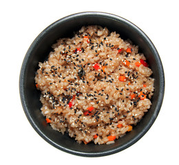Rice with vegetables and sesame in the black bowl. Isolated on white background.