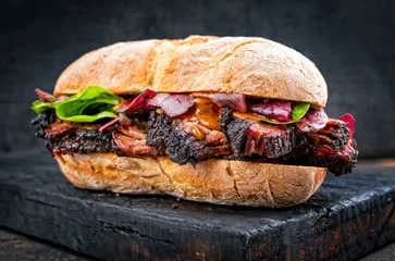 Poster Traditioneel barbecue pulled pork stukje Bosten butt als sandwich met sla als close-up op een zwart bord © HLPhoto