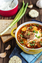 Traditional Ukrainian borsch with meat. Plate of red beetroot soup on rustic background. Traditional Ukraine food cuisine