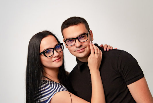 Lovely smiling couple wearing spectacles looking at camera over the white background. Portrait of pretty man and woman in modern eyeglasses