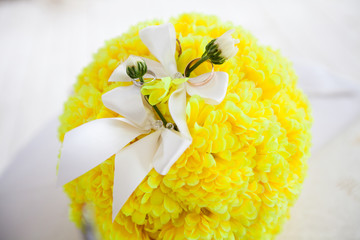 A pair of wedding rings on a bouquet of yellow flowers, close up shot