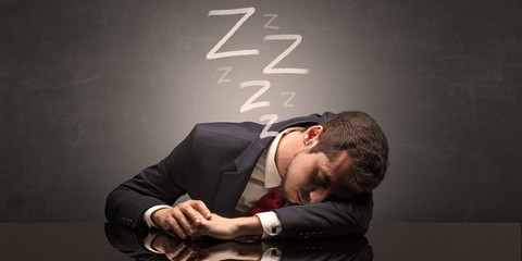 Young businessman fell asleep at the table concept