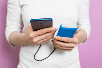 The woman uses a mobile phone, a smartphone, charged from the power bank. 