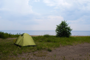 Green tent on the shore near the lake
