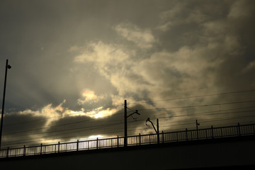 Railroad crossing bridge at the time of sunrise on a winter day. The sun hides among the clouds. Barrio de Salburua, in the city of Vitoria-Gasteiz (The Basque Country)