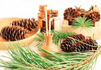Pine tree aromatherapy, green needles boughs, cones, aromalamp with sticks on table with natural branches, winter scents.