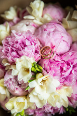 A pair of wedding gold rings on a bouquet of colorful flowers, close up shot