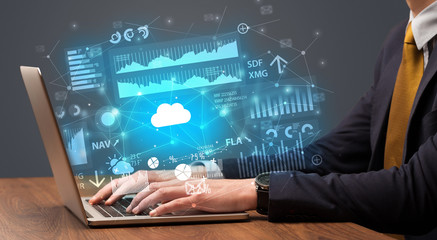 Businessman hand typing on laptop with reports and graphs concept around
