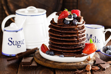 Stack of chocolate pancakes with berries, strawberry, raspberry and blueberry