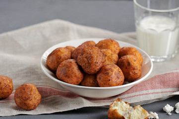 Cottage cheese balls, toasted in oil. Under the plate cloth napkin. Behind the plate is a glass of milk. Close-up.