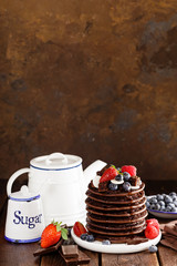 Stack of chocolate pancakes with berries, strawberry, raspberry and blueberry
