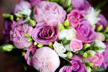 A pair of wedding gold rings on a bouquet of colorful flowers, close up shot