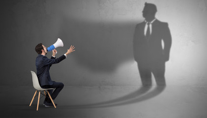 Obraz premium Humble businessman staying and offering stuffs to a huge businessman shadow