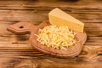 Cutting board with grated cheese on wooden table