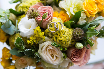 A pair of wedding gold rings on a bouquet of colorful flowers, close up shot