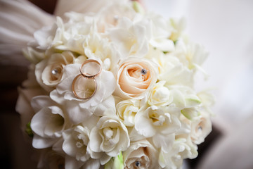 A pair of wedding rings on a bouquet of white flowers, close up shot