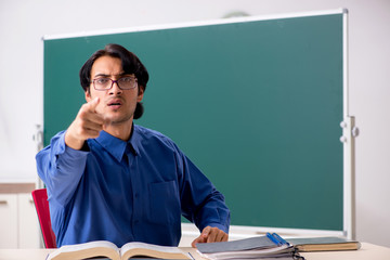 Young male teacher in front of chalkboard  