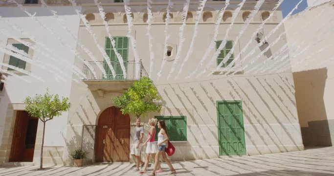 Europe Travel Vacation In Mallorca Spain Alcudia Old Town - Tourists Walking in Street, Majorca, Balearic Islands Spain, Europe. Group of friends walking having fun on travel vacation holidays.