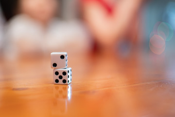 Play dice on the table, kids silhouettes in the background.