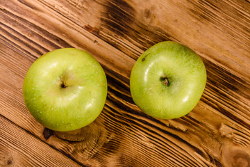 Two ripe green apples on a wooden table. Top view