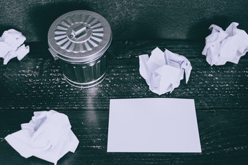 garbage bin on desk setting with empty notepad and scrunched paper balls